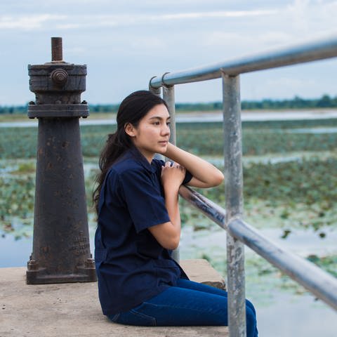 Asian girl sitting on jetty (Foto: IMAGO, Panthermedia)