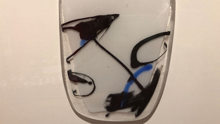 Eine flache Glaskachel mit weißem Hintergrund und schwarzen und weißen Schwüngen darauf. (Foto: SWR, Natali Kurth) Eine flache Glaskachel mit weißem Hintergrund und schwarzen und weißen Schwüngen darauf.