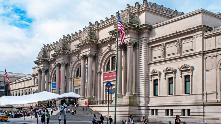 Das Metropolitan Museum of Art in New York: Altes neoklassisches Gebäude an einer Straße mit vielen Menschen.