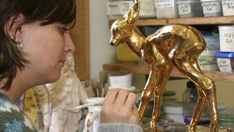 Keramikmalerin bemalt Bambi-Figur mit goldener Farbe. (Foto: picture-alliance / Reportdienste, Maria Figiel) Keramikmalerin bemalt Bambi-Figur mit goldener Farbe.