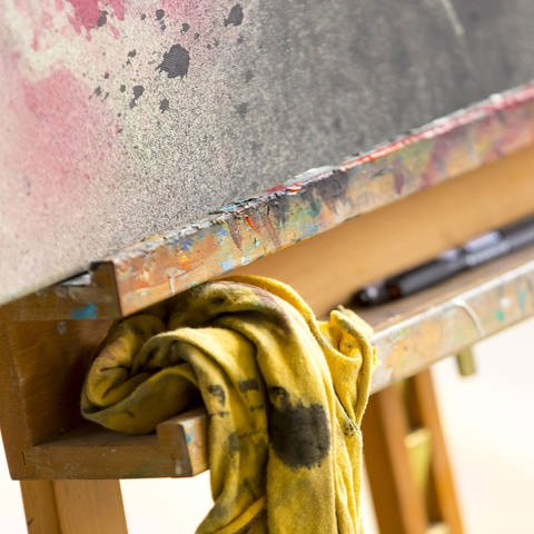 Auf einer Staffelei liegt ein mit Farbe beschmiertes Tuch und Pinsel (Foto: IMAGO, Agentur 54 Grad Felix König)