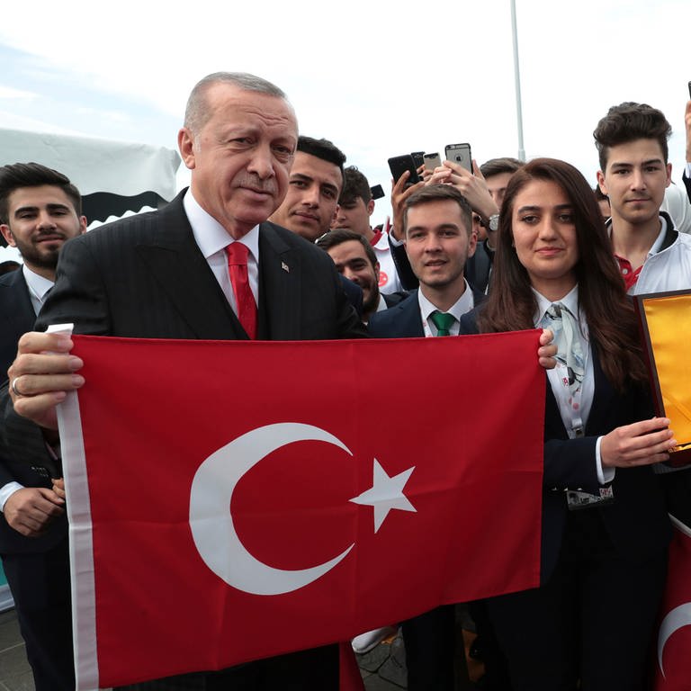 Dieses vom Presidential Press Service zur Verfügung gestellte Bild zeigt Recep Tayyip Erdogan (l), Präsident der Türkei, der eine türkische Nationalflagge hochhält (Foto: picture-alliance / Reportdienste, dpa Bildfunk, picture alliance/dpa/Pool Presidential Press Service/AP | Uncredited)