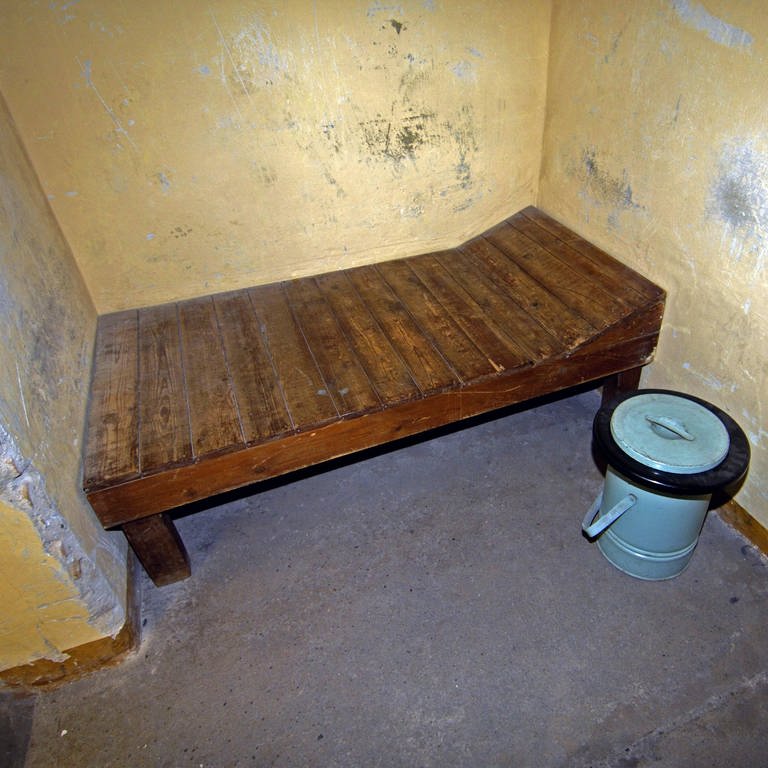 Holzpritsche in einer Gefängniszelle