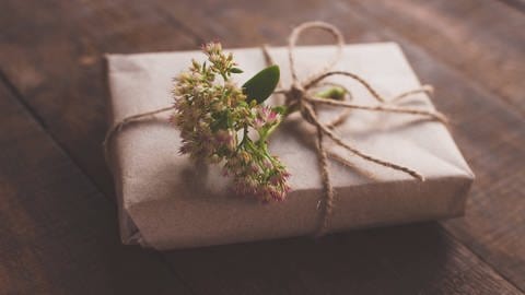 Ein Buch ist in Geschenkpapier verpackt und mit einer Blume geschmückt. 