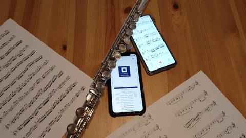 Begleit-Apps für Musiker*innen: Auf einem Tisch liegen zwei Smartphones, eine Querflöte und Notenblätter