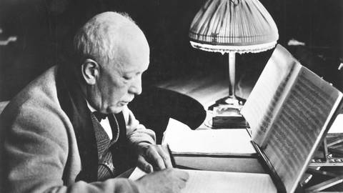 Schwarz-Weiß-Aufnahme des betagten Richard Strauss an seinem Schreibtisch. (Foto: IMAGO, IMAGO / GRANGER Historical Picture Archive)