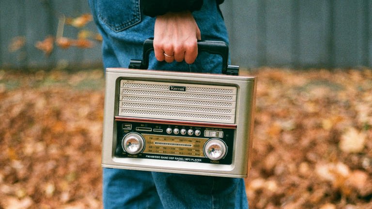 Ein Mann hat ein Radio in der Hand, das er im Freien trägt  (Foto: Colourbox, Olena Bohovyk)