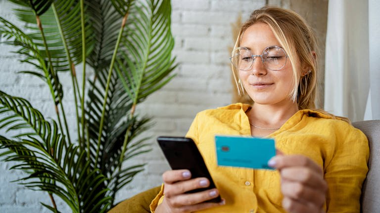 Eine Frau bezahlt online mit Smartphone und Kreditkarte