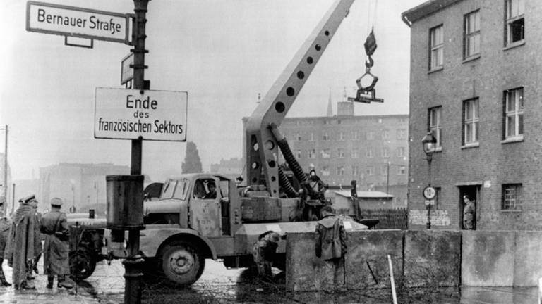 15. August 1961: Die DDR-Volkspolizei verstärkt die Stacheldrahtsperre zwischen der sowjetischen und der französischen Zone von Berlin. Schwere Betonplatten werden errichtet, um Ost-Berlin von den Westsektoren abzugrenzen. 