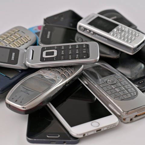 Viele gebrauchte Handys, die auf dem Müll landen, auf einem Haufen geschichtet.