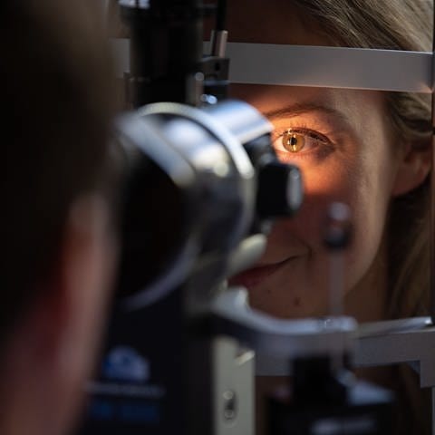 Ein Arzt untersucht das Auge einer Patientin 