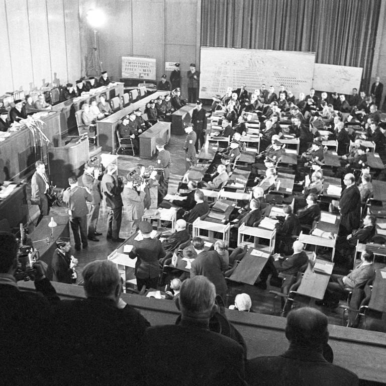 Blick in den Saal des Frankfurter Rathauses, wo 22 ehemalige Wachen und Beamte (rechts abgebildet mit ihren Anwälten und Polizisten) des Konzentrationslagers Auschwitz vor Gericht gestellt wurden. Sie waren für die Tötung von mehr als 2 12 Millionen Menschen im Lager verantwortlich. (Aufnahme vom 20. Dezember 1963)