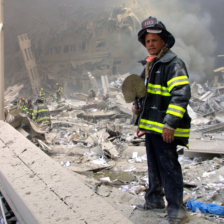 Ein Feuerwehrmann steht nach den Anschlägen des 11. September 2001 in New York mit einer Schaufel in den Trümmern eines Gebäudes (Foto: picture-alliance / Reportdienste, picture alliance / ASSOCIATED PRESS | Shawn Baldwin)