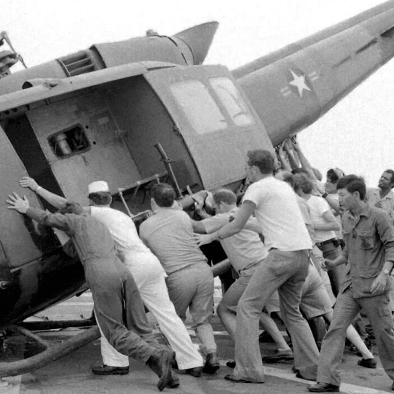Menschen versuchen, in einen Hubschrauber zu gelangen: Dem Fall der Stadt Saigon ging die Evakuierung fast des gesamten amerikanischen Zivil- und Militärpersonals voraus, zusammen mit Zehntausenden südvietnamesischer Zivilisten, die mit dem südlichen Regime in Verbindung standen. Die Evakuierung gipfelte in der "Operation Frequent Wind", der größten Hubschrauberevakuierung der Geschichte.