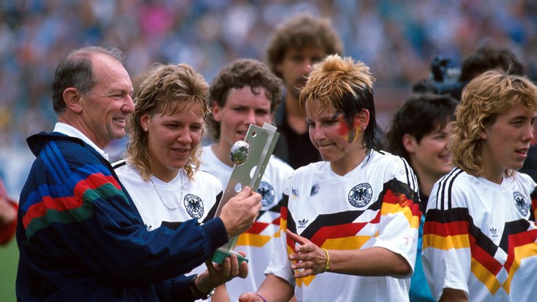 Fußball-Bundestrainer Gero Bisanz übergibt den EM-Pokal an Spielerin Ursula Lohn (2.v.r.)