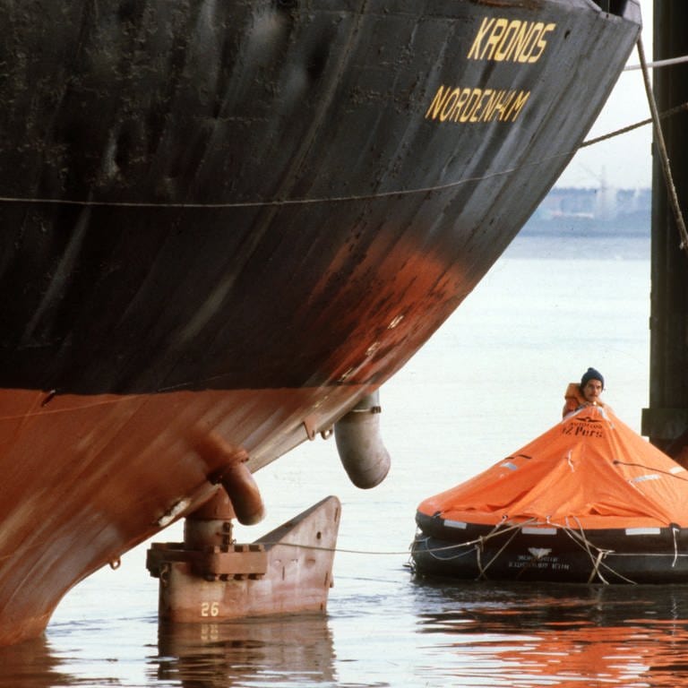Mitglieder der Umweltschutzorganisation Greenpeace schwimmen am 13.10.1980 in einer roten Rettungsinsel vor dem Bug des Abfalltankers "Kronos", der in Nordenham auf der Weser vor Anker liegt