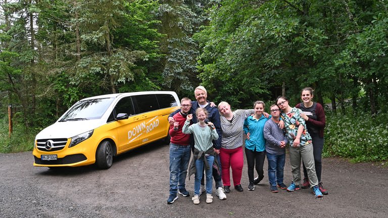 Die Reisegruppe steht vor ihrem Tourbus im Wald an der Geierlaybrücke