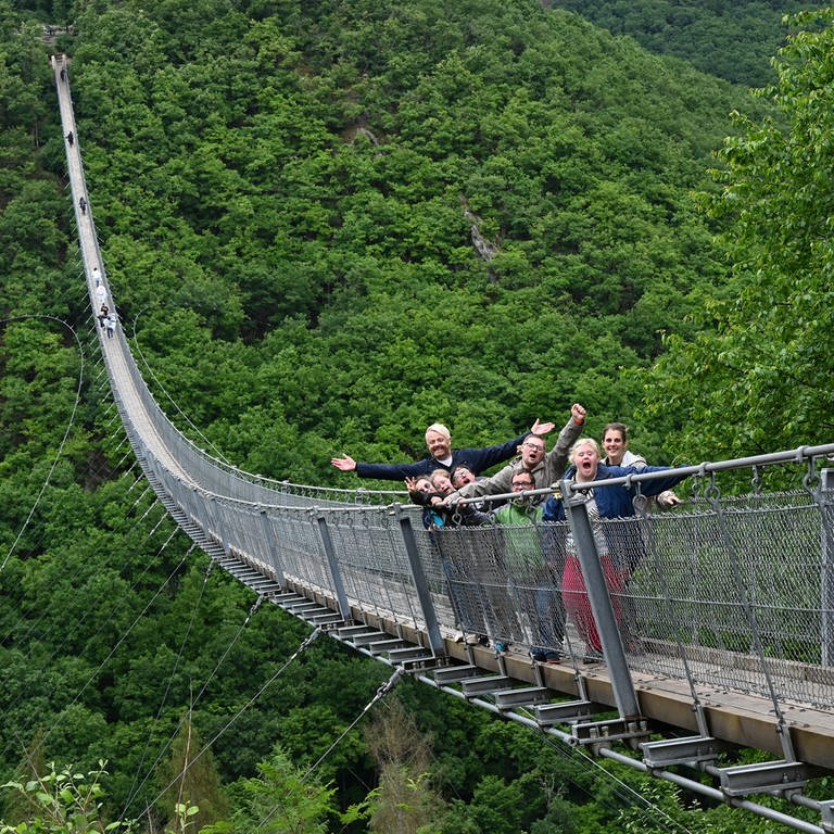 Die Gruppe überquert die Hängeseilbrücke Geierlay in atemberaubender Höhe inmitten des Waldes
