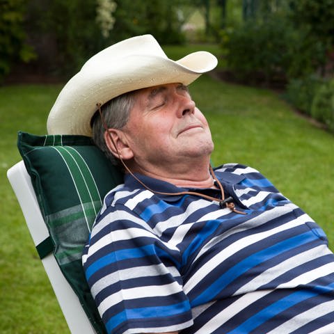 Powernapping: Mann mit Hut beim Mittagsschlaf im Garten