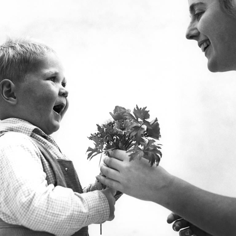 Kleiner junge überreicht Blumen zum Muttertag (1960er-Jahre)