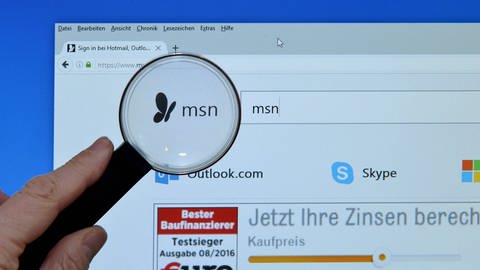 Lupe vor Bildschirm mit msn-Logo, dem Nachrichtenportal von Microsoft