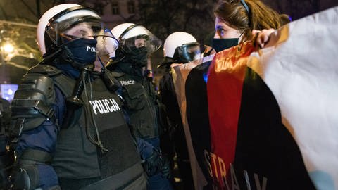 Frau mit Plakat steht mutig vor einer Reihe von Polizisten: 28. Januar 2021, Warschau: "Strajk Kobiet" oder "Streik der Frauen" in Polen