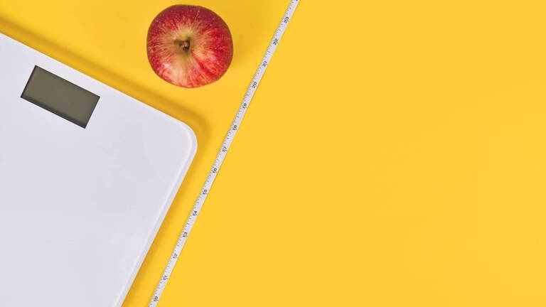 Waage, Apfel und Maßband vor gelbem Hintergrund (Foto: IMAGO, IMAGO / imagebroker)