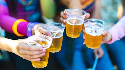 Gerade die Mischung von Energydrinks mit Alkohol kann schlecht für unseren Körper und unsere Gesundheit sein. Menschen stoßen mit Long Drinks an.